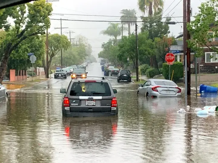 Storm water filling a palm-lined street after a winter storm near South Gate